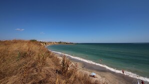 A beach with clear skies, a sandy shore, and a few people enjoying the water. - Menada Ravda Apartments (Pomorie)
