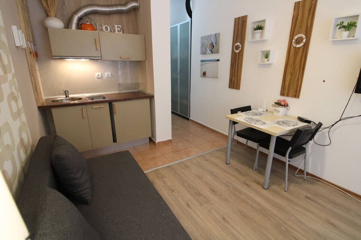 A compact living space with a kitchenette, a dining area, and a sofa.