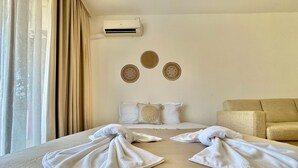 A hotel room with a bed, two pillows, a sofa, and an air conditioning unit on the wall. - Menada Ravda Apartments (Pomorie)