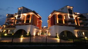 A symmetrical building with multiple balconies and arched entrances, likely part of a hotel or residential complex. - Menada Ravda Apartments (Pomorie)