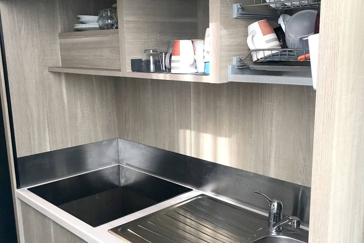 A modern kitchen with two stainless steel sinks, a built-in oven, and a dish drying rack.