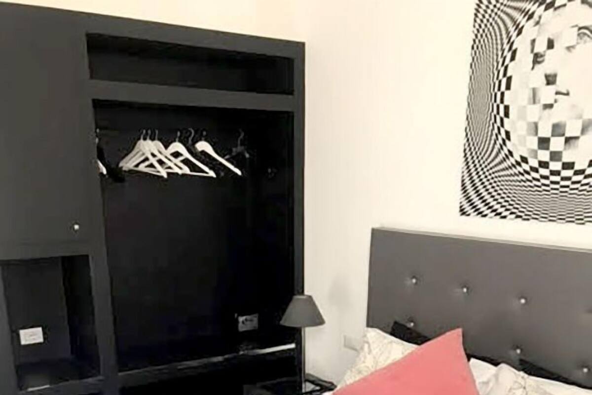 A bedroom with a bed, a wardrobe, and a wall art piece.