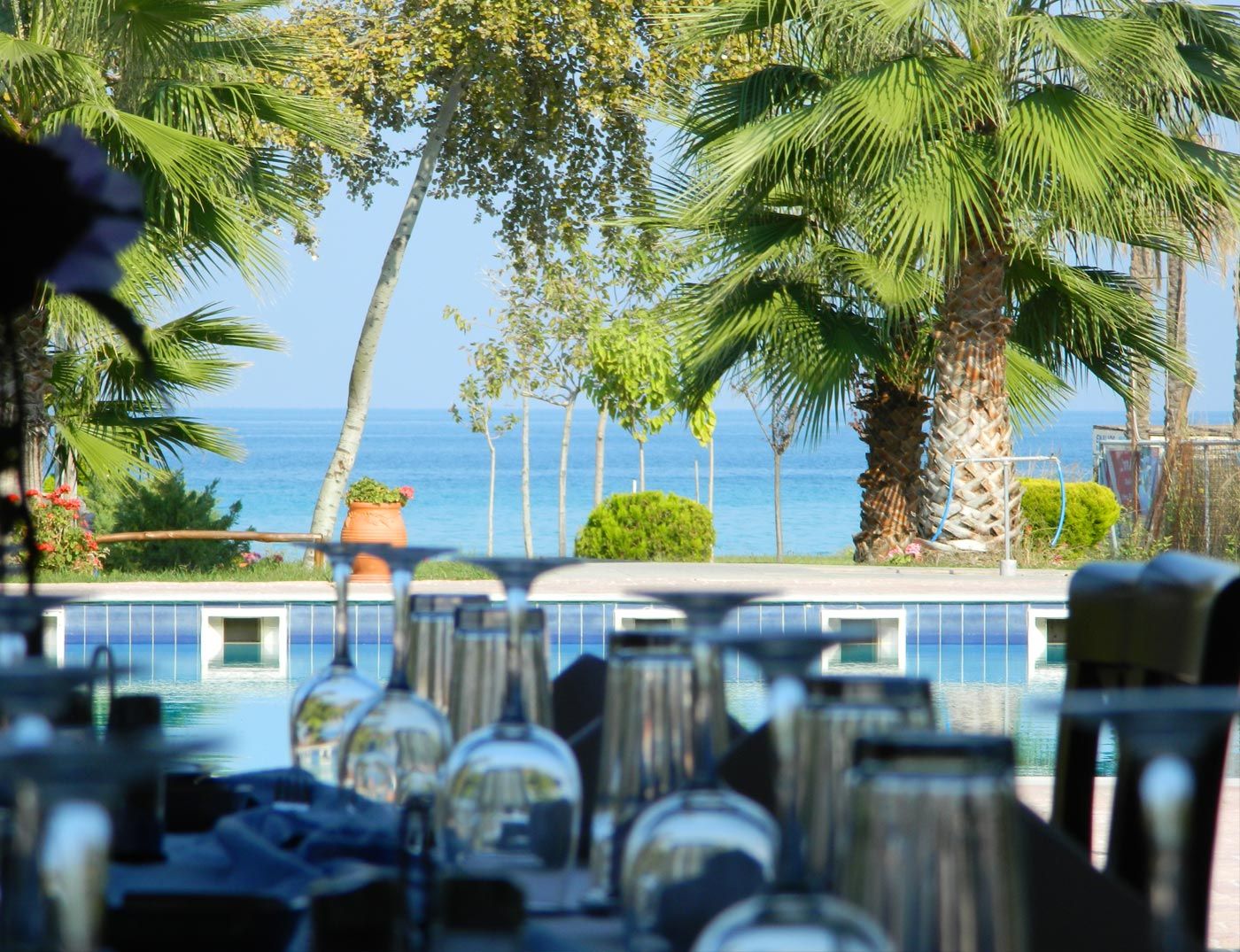 A pool area with lounge chairs and a view of the sea.