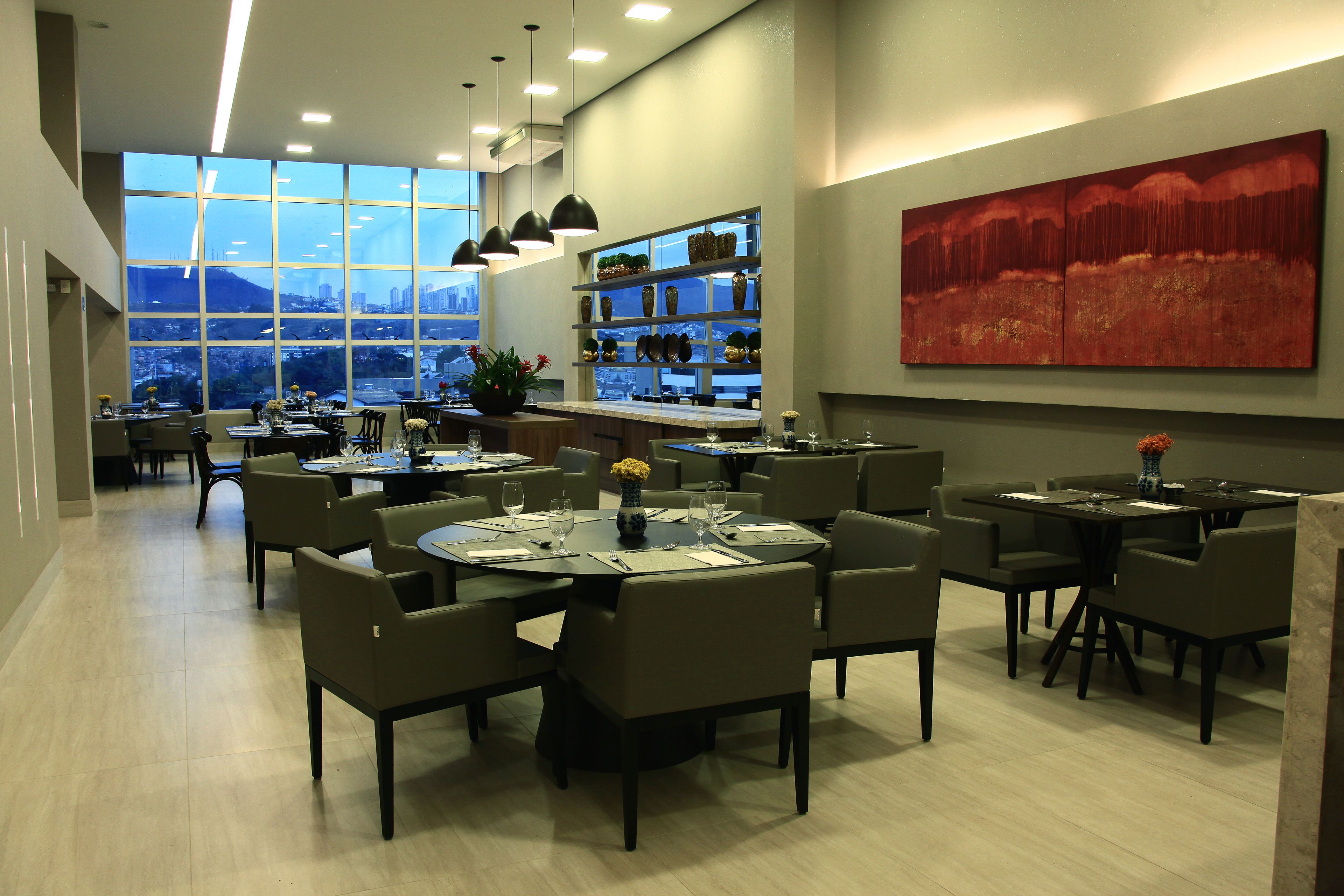 A modern restaurant with multiple dining tables, chairs, and pendant lighting.