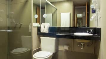 Et moderne badeværelse med en brusekabine i glas, et hvidt toilet, en vask og et spejl over vasken.