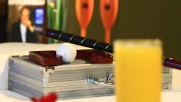 Una mesa con una pelota de golf, un palo de golf y un vaso de jugo de naranja.