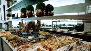 Un bufé con diversos alimentos y plantas decorativas en estantes.