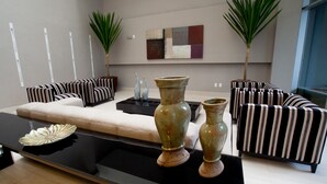 Un salón moderno con sofás a rayas, una mesa de centro de cristal y jarrones decorativos.