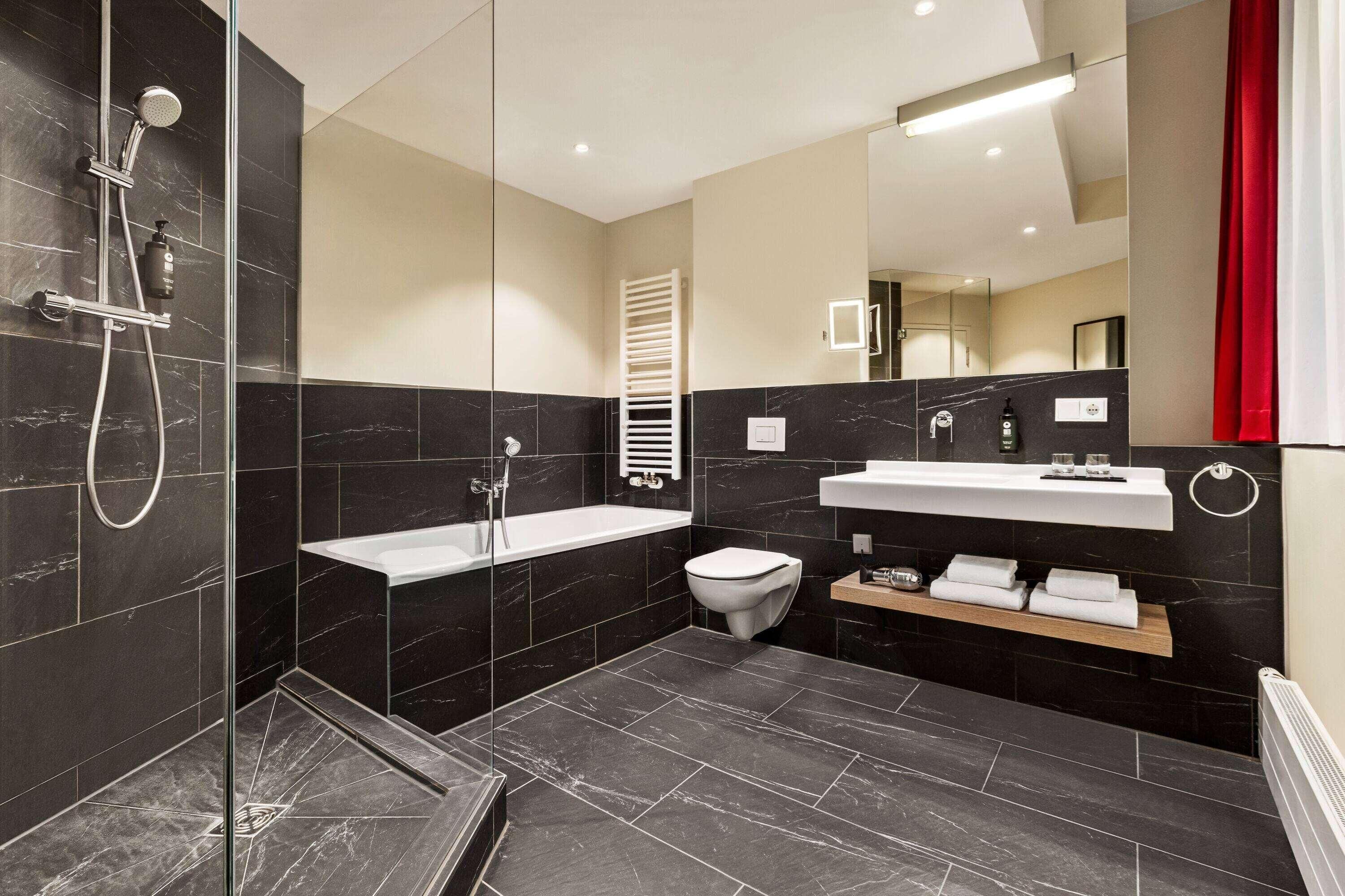 A modern bathroom with a glass-enclosed shower, a white sink, and a toilet.