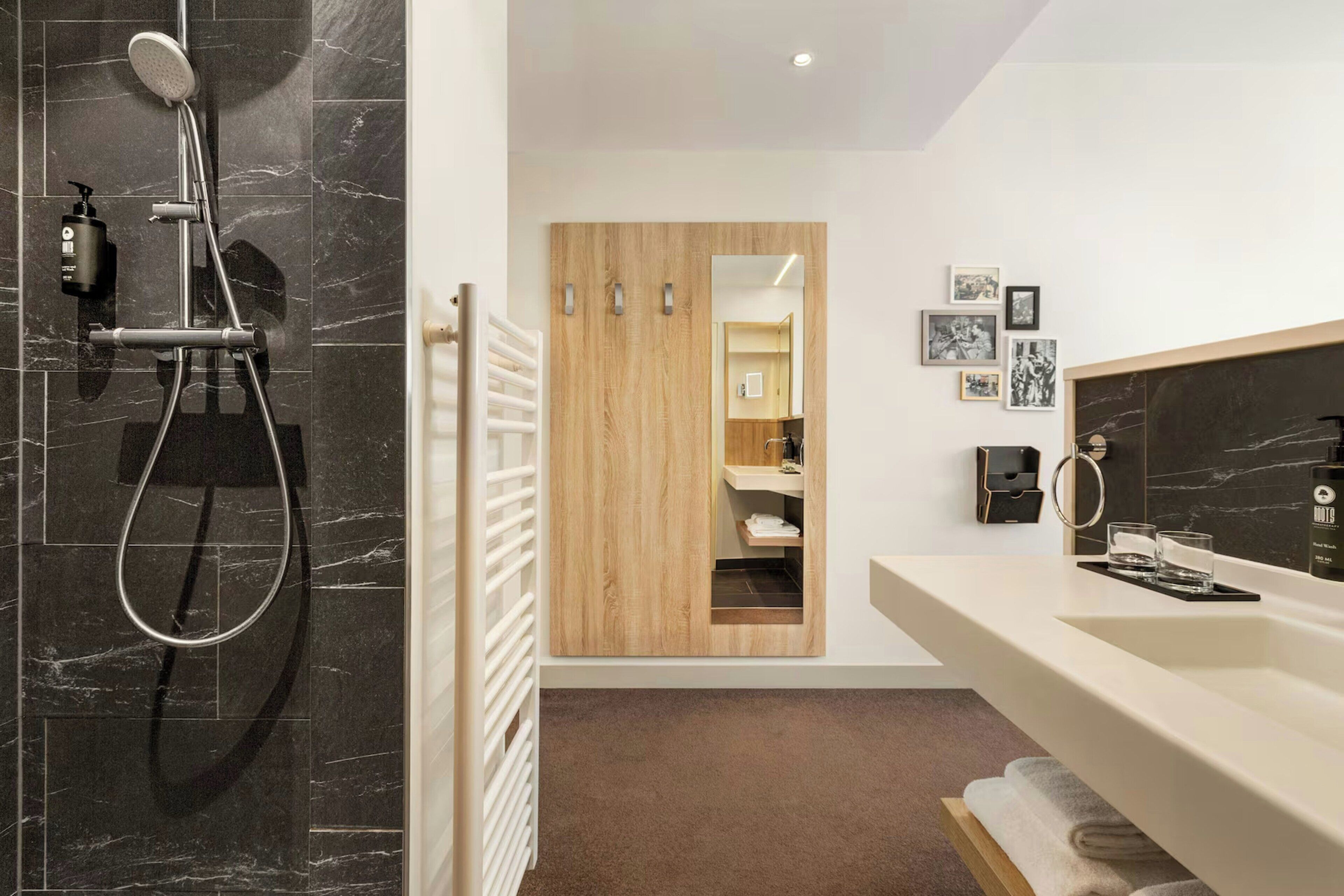 A modern bathroom with a shower, a vanity with a mirror, and a towel rack.