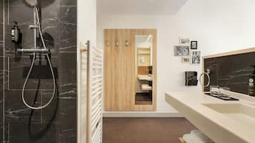 A modern bathroom with a shower, a vanity with a mirror, and a towel rack.