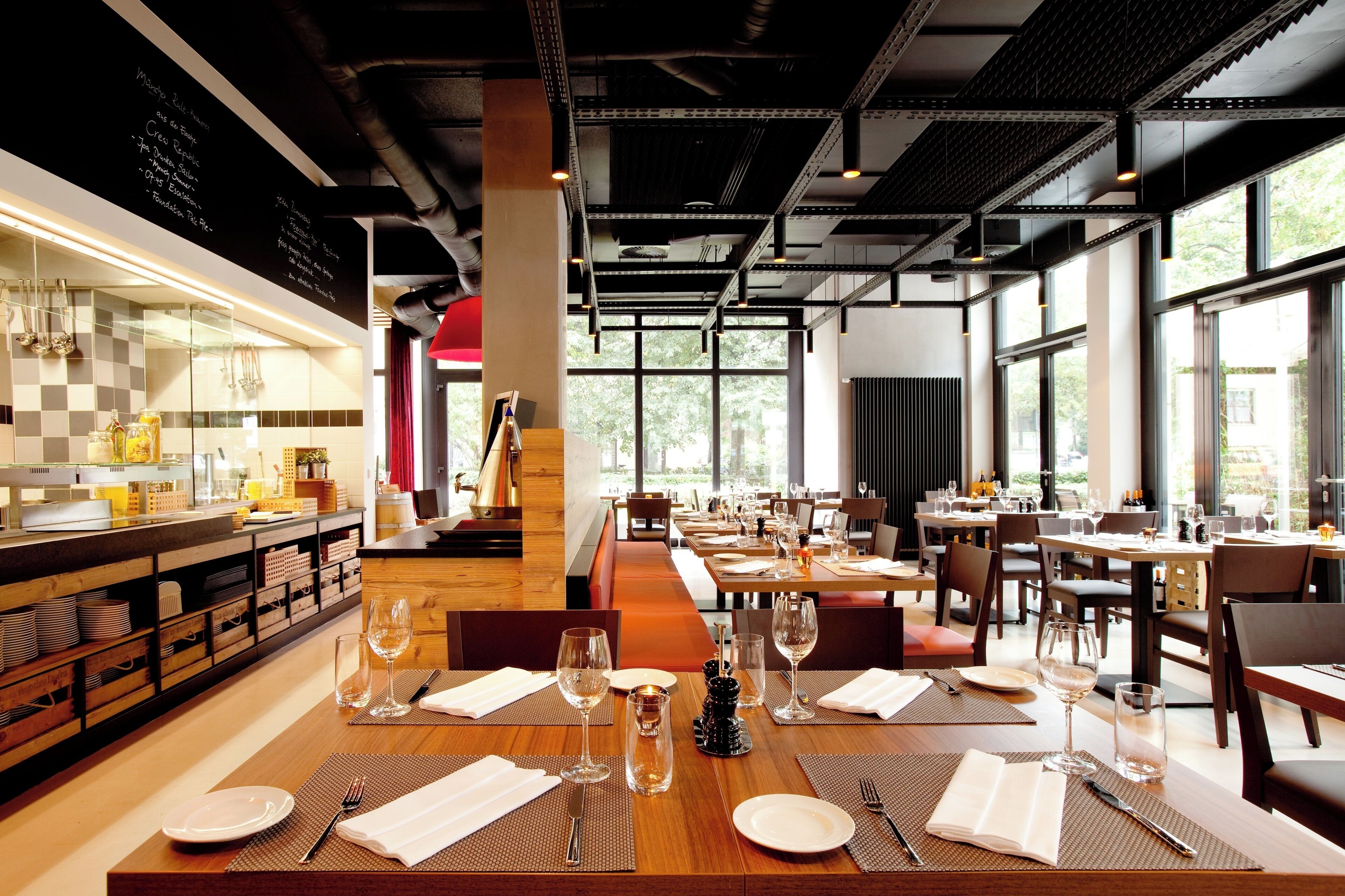 Un restaurant avec des tables en bois, des assiettes blanches et des verres à vin disposés pour le repas.