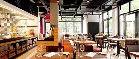 Un restaurant avec des tables en bois, des assiettes blanches et des verres à vin disposés pour le repas.