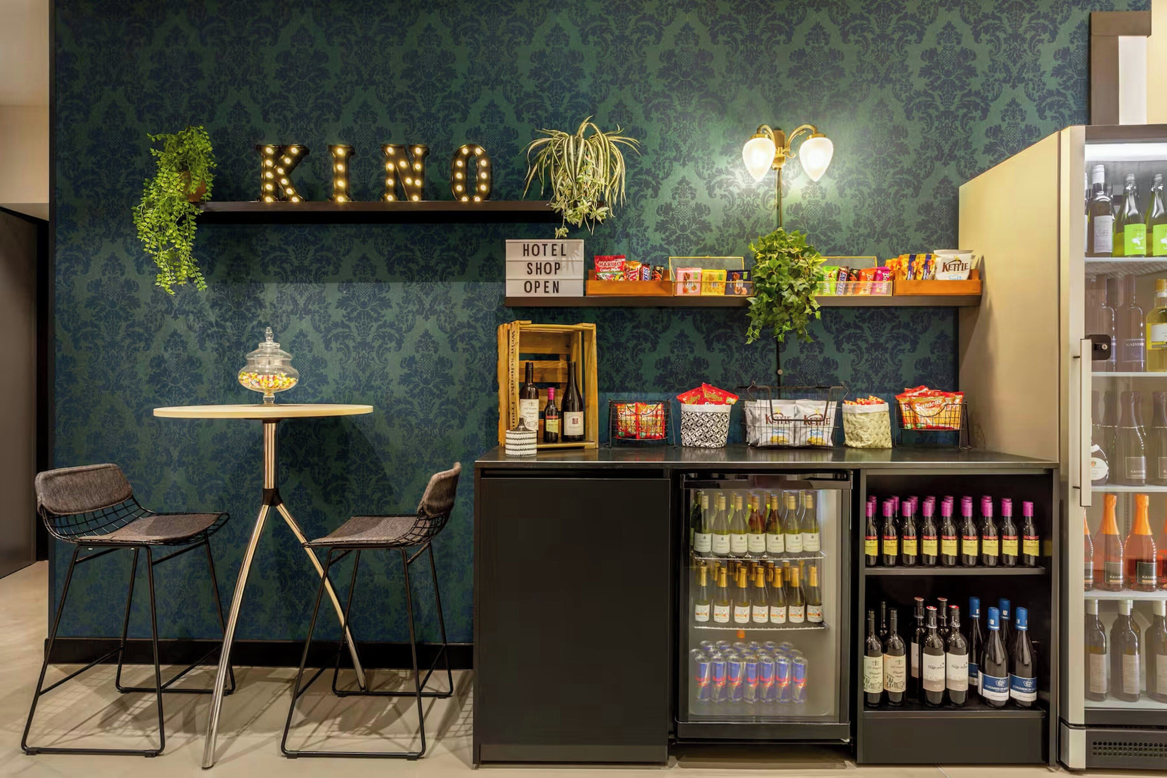 A hotel shop with a variety of snacks and beverages, a sign indicating it's open, and a display of wine bottles.