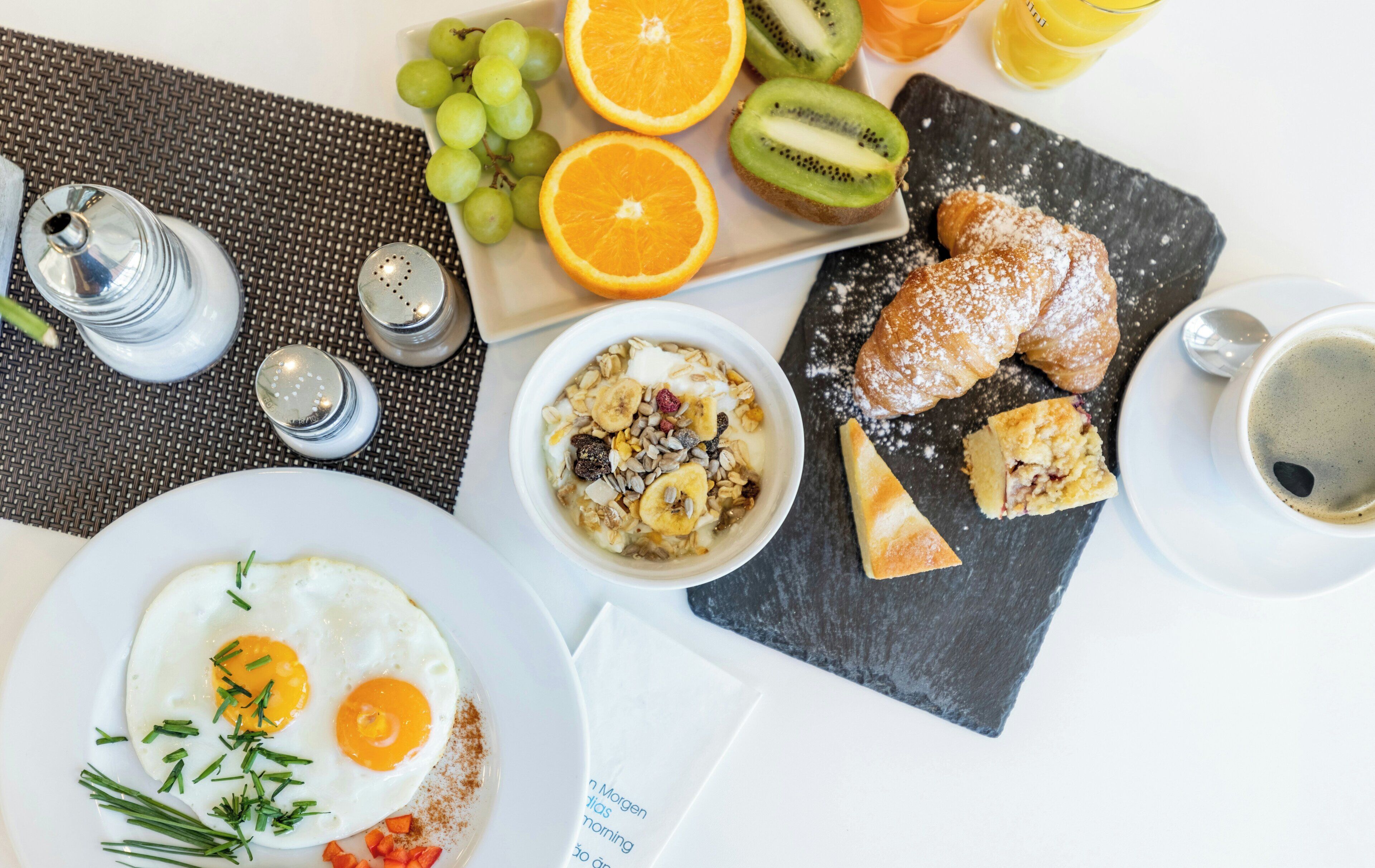 Desayuno con huevos, tostadas, fruta y una taza de café.