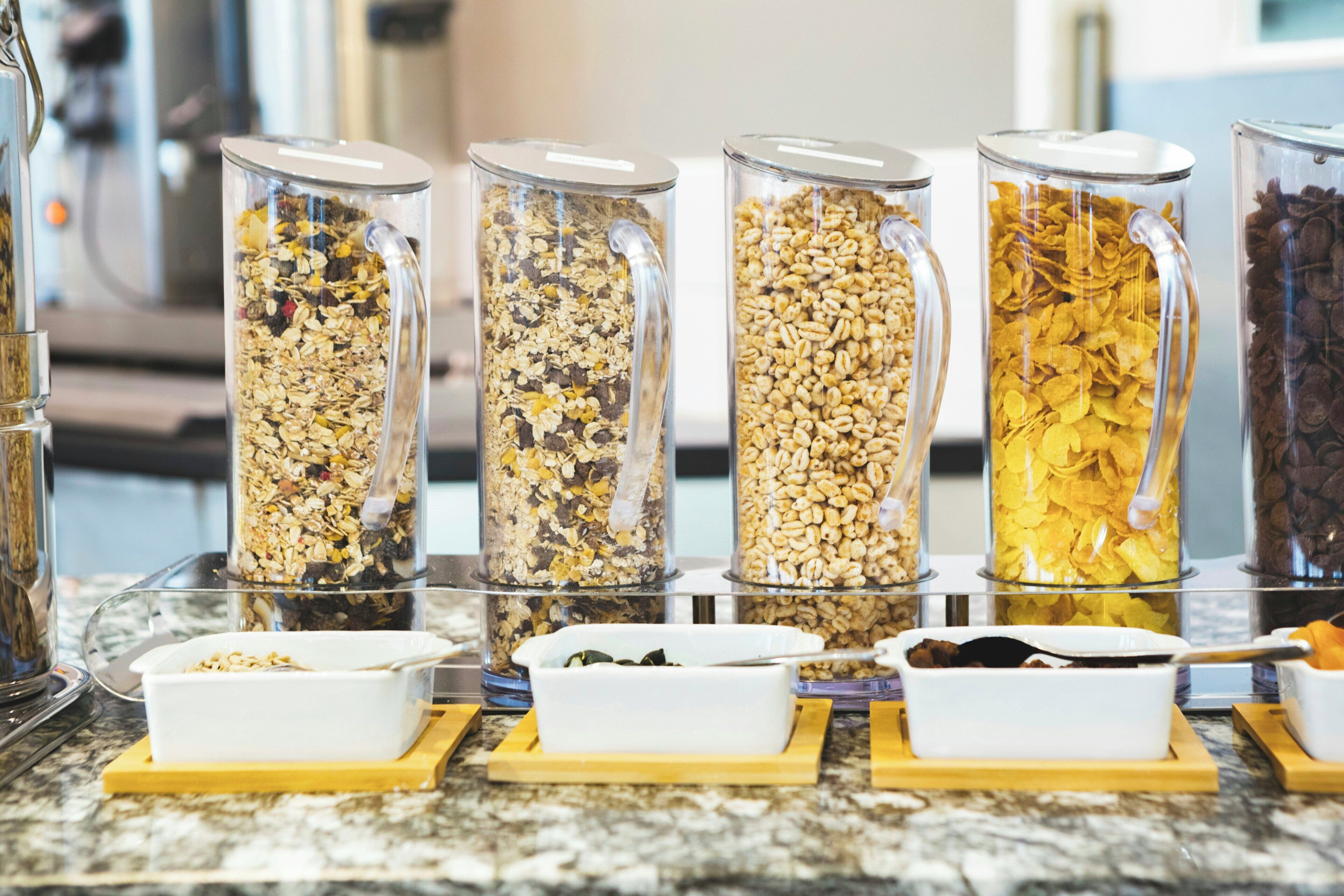 Una barra de desayuno con varios recipientes de granola y cereales.