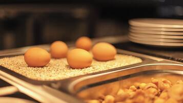A buffet with trays of eggs and a pile of cereal.