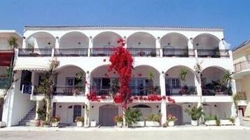 A multi-story building with a white facade, multiple balconies, and a central red flower arrangement.
