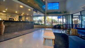 A modern hotel lobby with a reception desk, seating area, and large windows offering views of the outdoors. - Bessa Beach Hotel (João Pessoa)