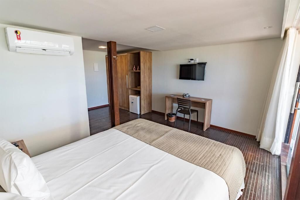Una habitación de hotel con una cama, un escritorio, un televisor y un equipo de aire acondicionado.