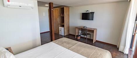 Una habitación de hotel con una cama, un escritorio, un televisor y un equipo de aire acondicionado.
