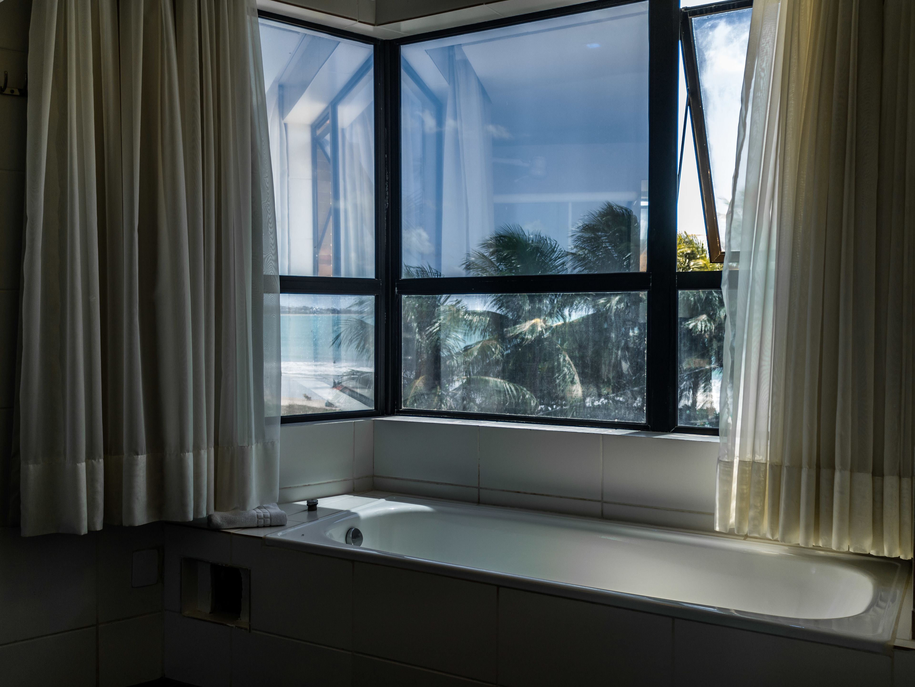 A bathroom with a large window, a bathtub, and a towel rack.