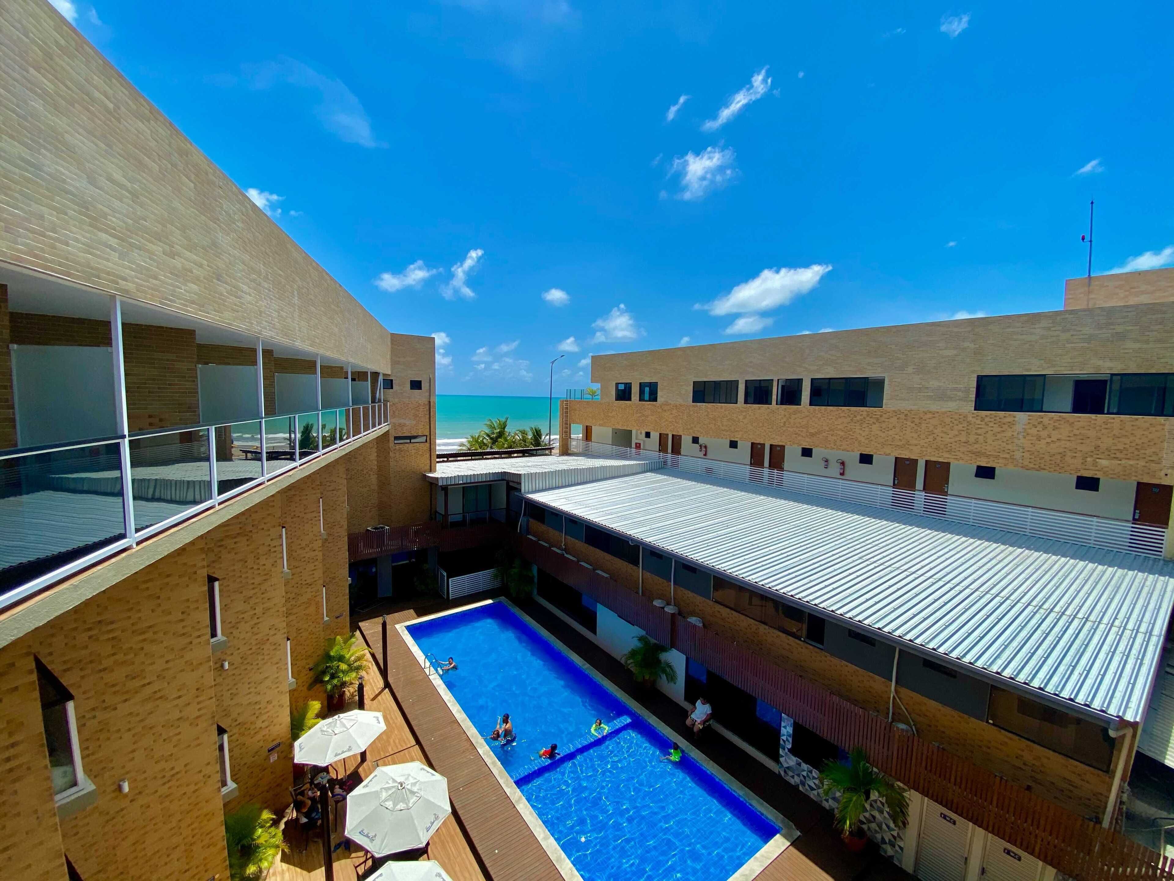 Un bâtiment moderne doté d’une piscine, de grandes fenêtres et offrant une vue sur l’océan.