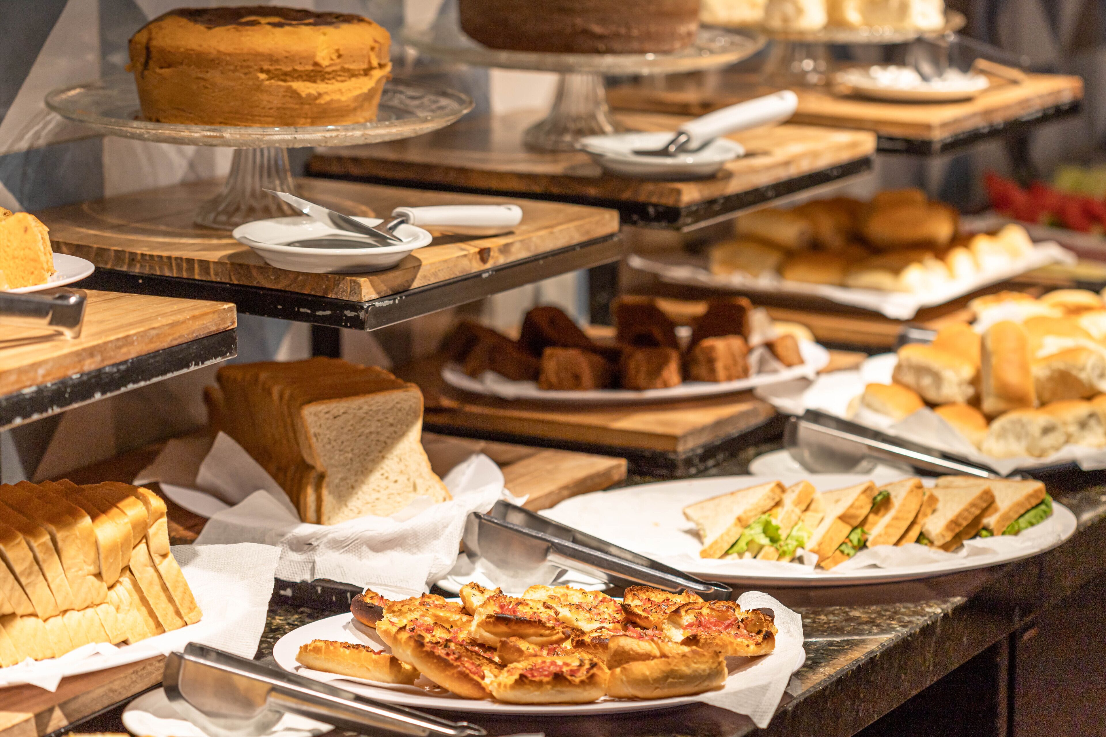 Een buffet met diverse gerechten, waaronder belegde broodjes, brood en een taart.