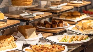 Een buffet met diverse gerechten, waaronder belegde broodjes, brood en een taart.