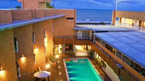 Un edificio moderno con piscina, iluminación exterior y vistas al océano.