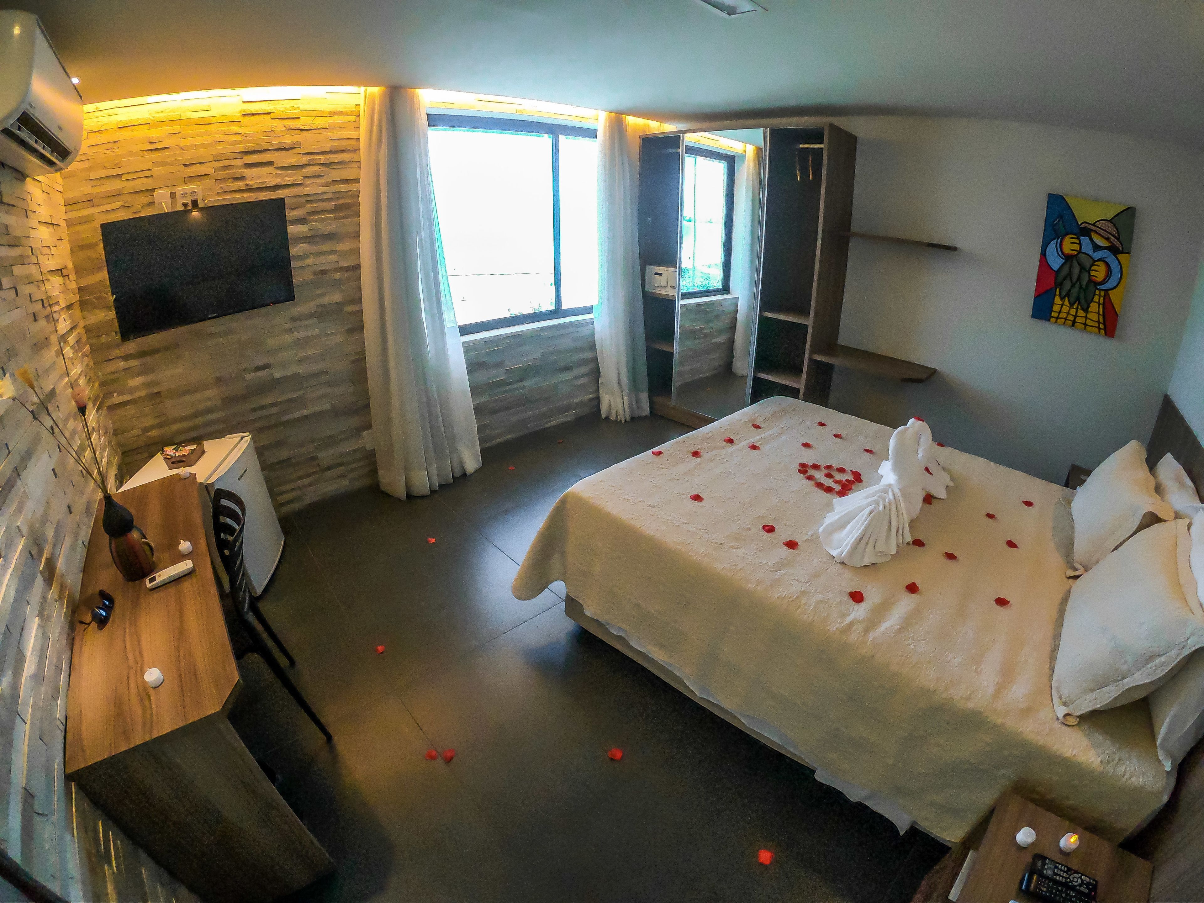 Une chambre d’hôtel avec un lit, un bureau, une télévision et une armoire.
