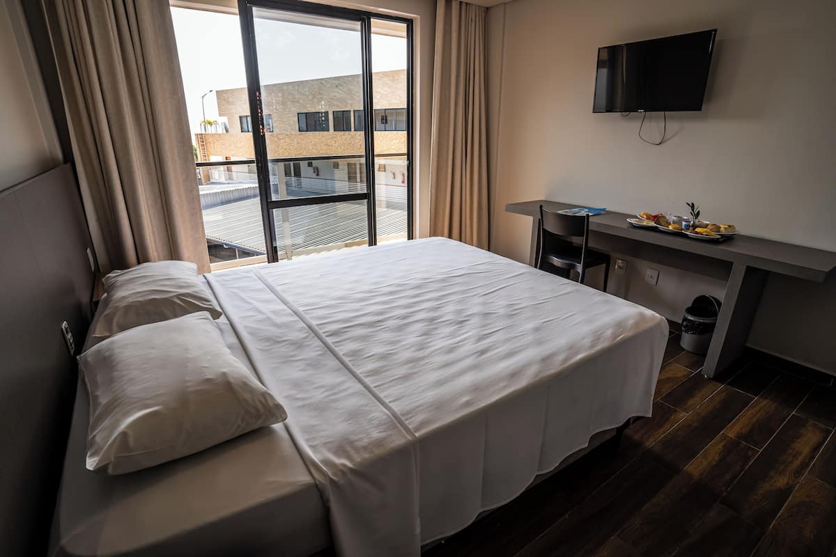 Camera d'albergo con un letto grande, una scrivania, una TV e vista sull'esterno.