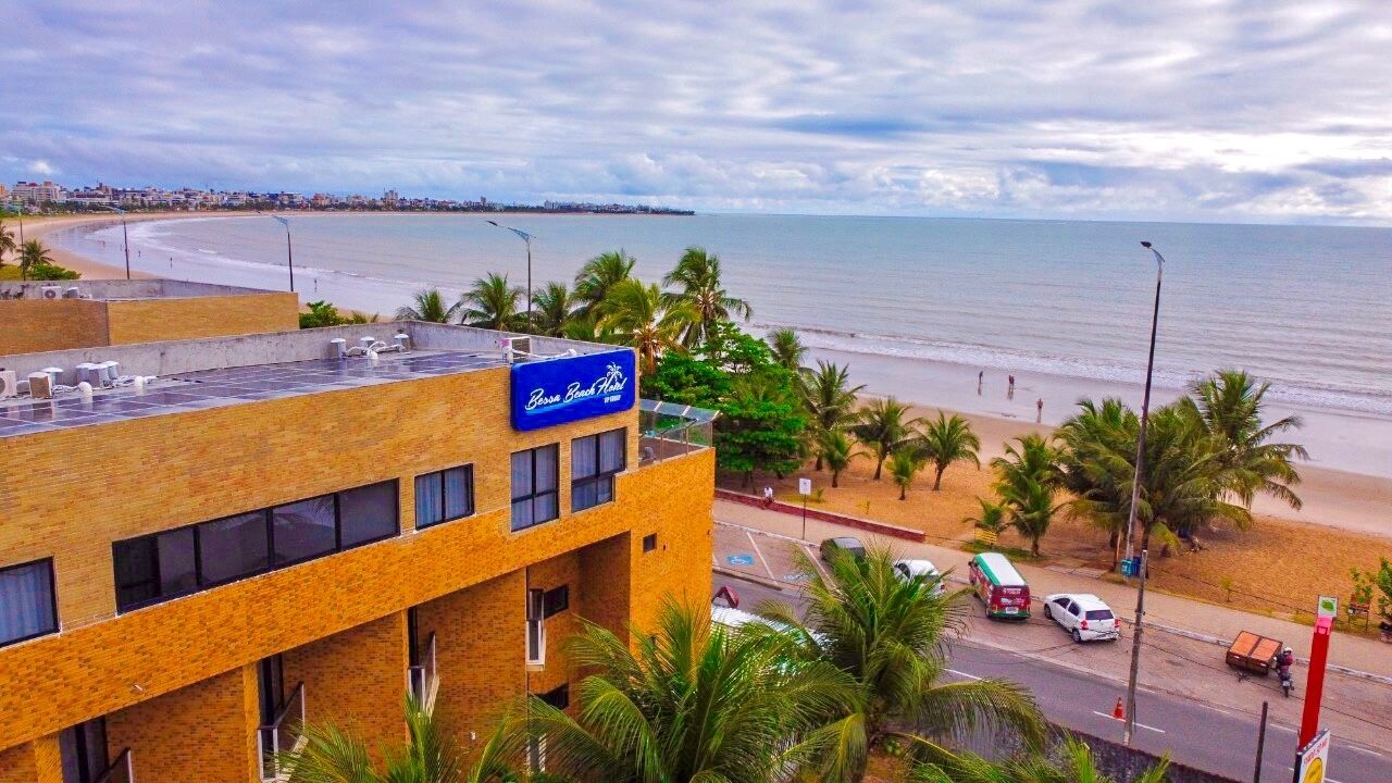 Hotel amb vista a la platja, zona d'aparcament i palmeres.