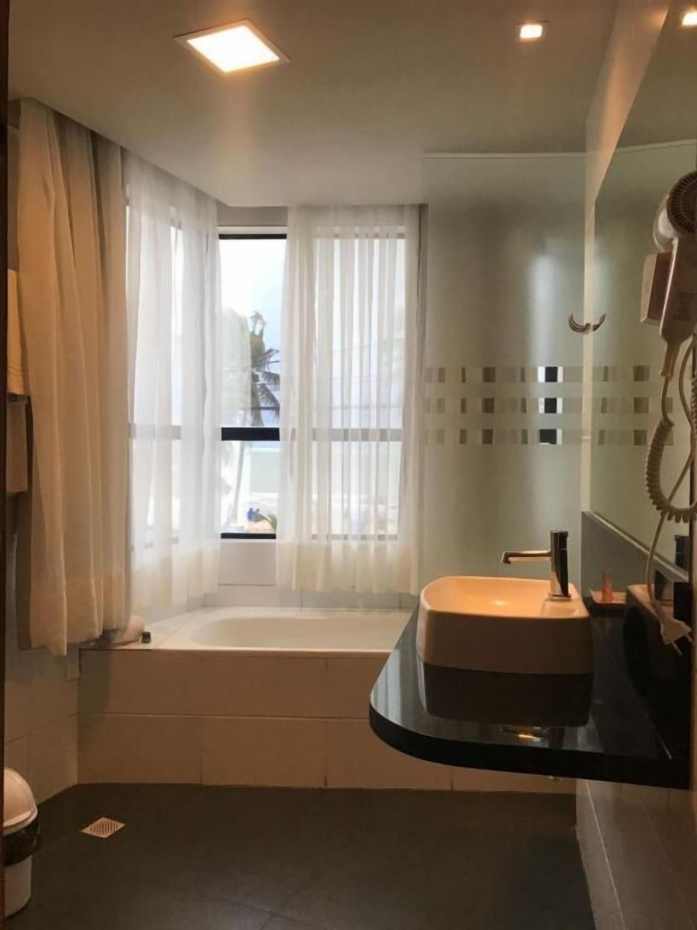 A modern bathroom with a bathtub, a sink, and a large mirror.