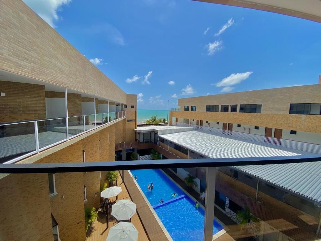 Ein modernes Gebäude mit Poolbereich, Glasgeländern und Meerblick.