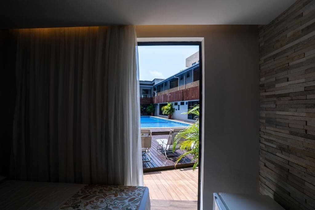 A bedroom with a view of an outdoor swimming pool and a wooden deck.