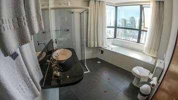 A modern bathroom with a black sink, a glass shower enclosure, and a toilet.