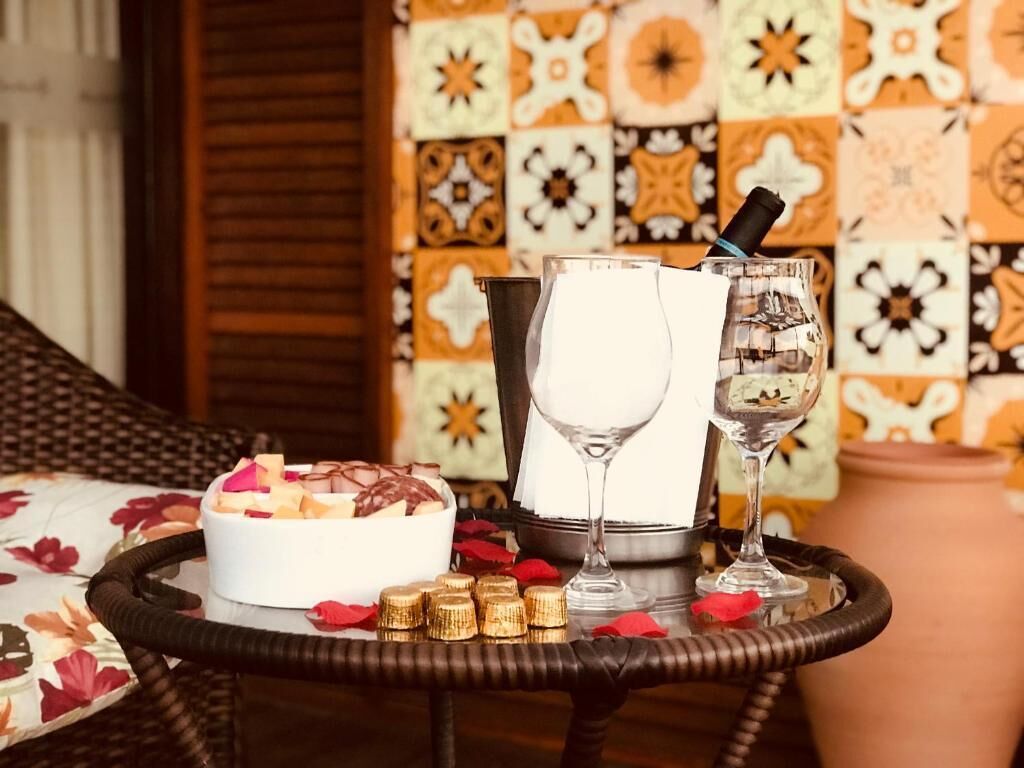 Un tavolino in vimini con una ciotola bianca piena di cibo, un bicchiere di vino, una bottiglia e una candela.
