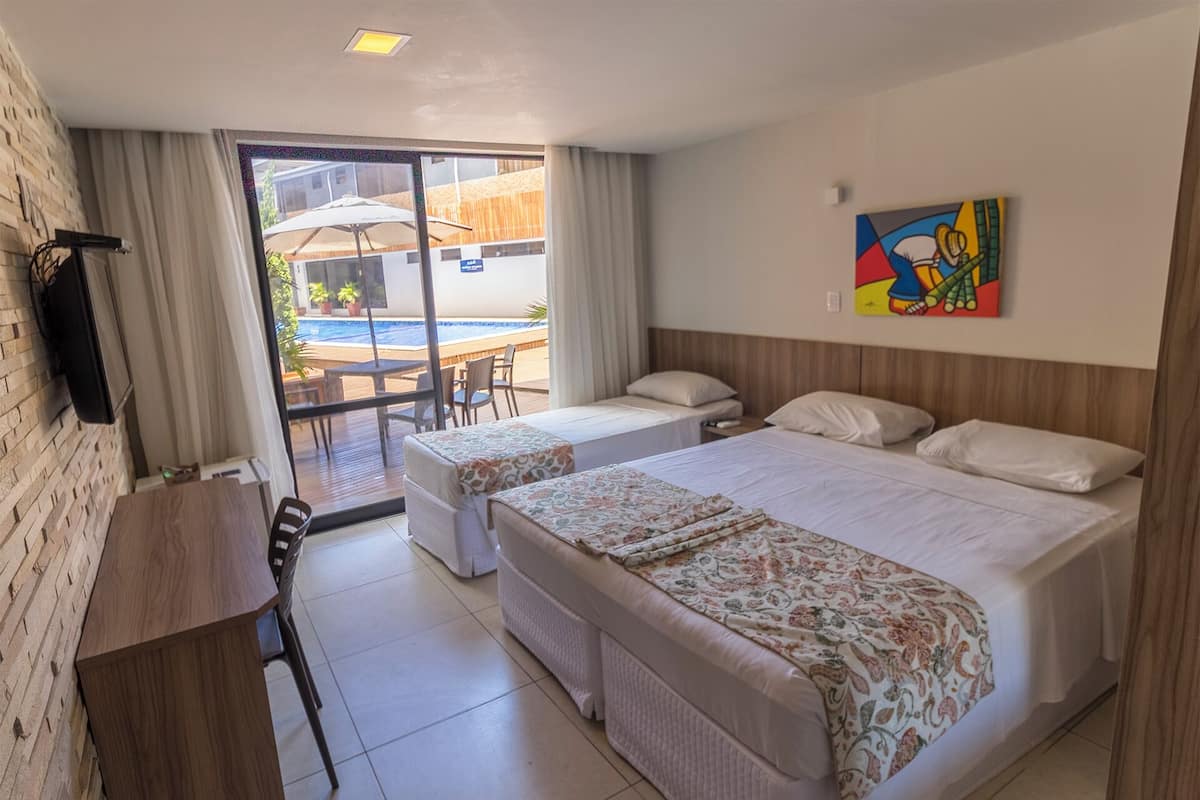 Camera d'albergo con due letti, televisione, scrivania e vista sulla zona della piscina esterna.