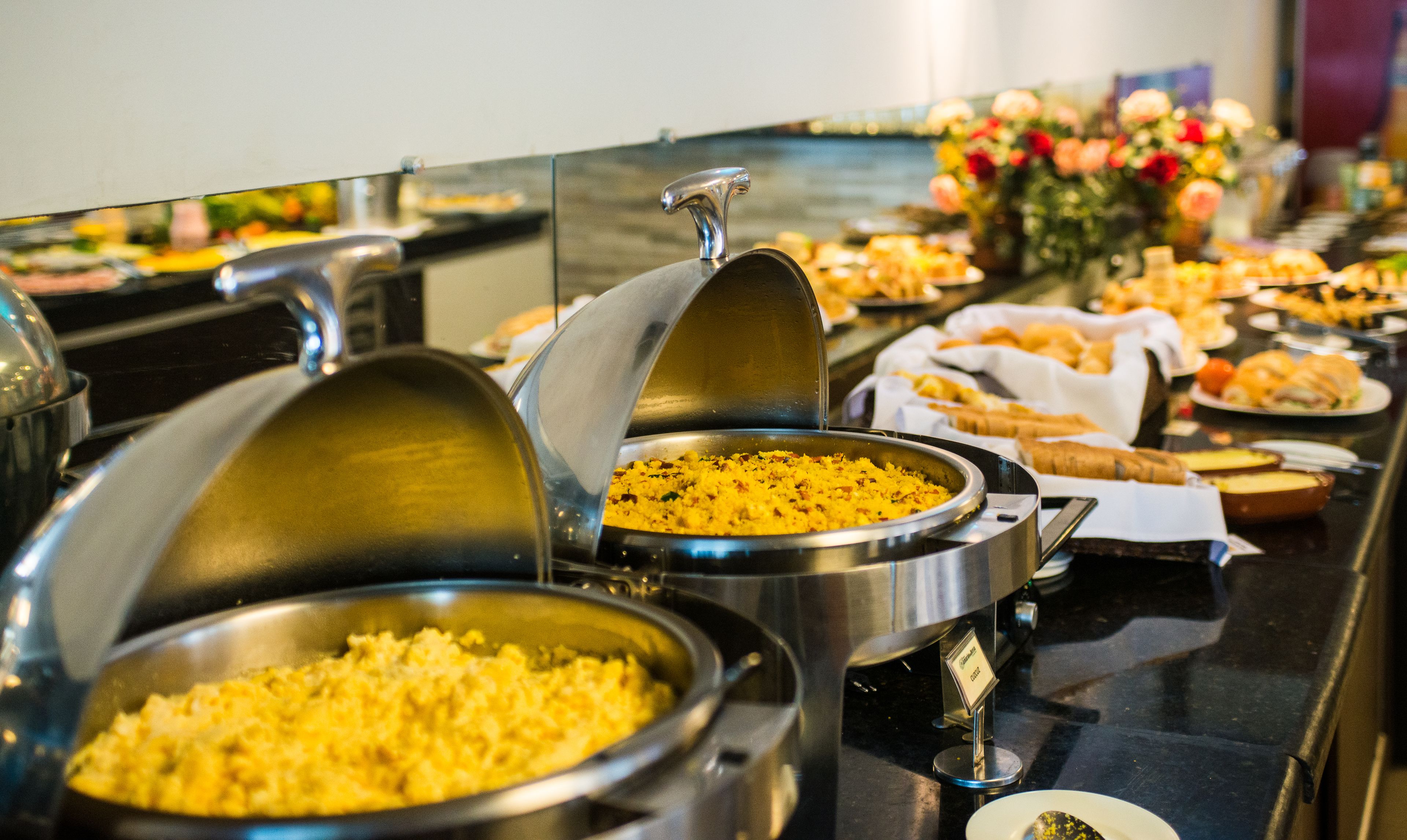 Un bufé con diferentes opciones de comida y un cartel que indica 'Desayuno por tipo de comida'.