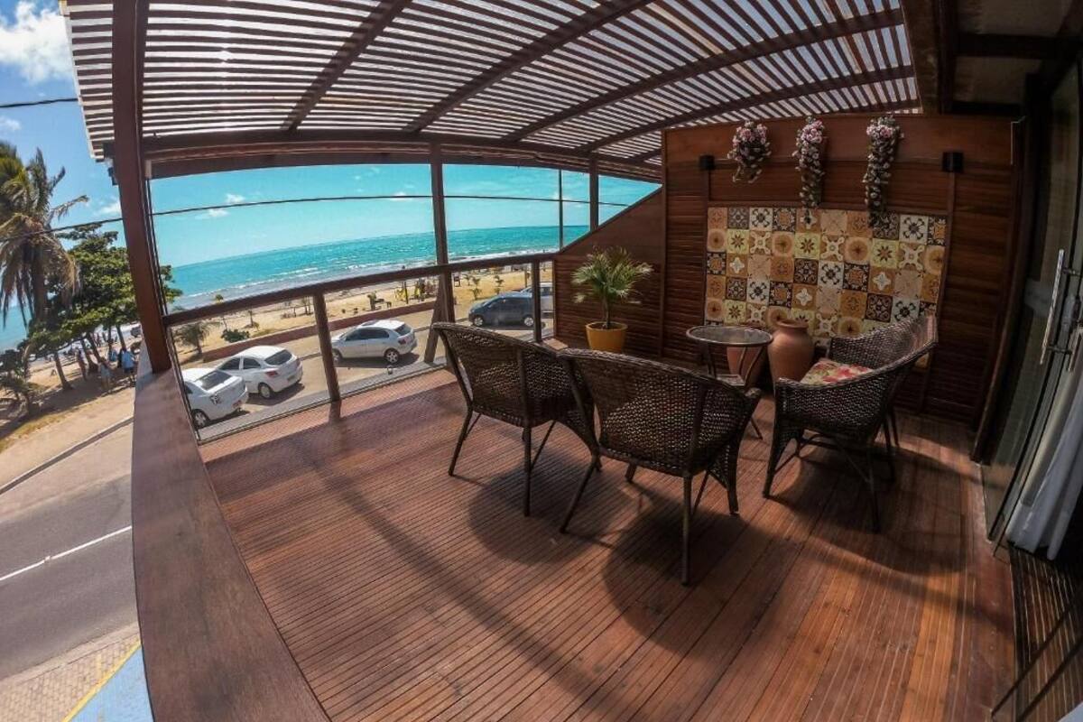 Un pontile in legno con sedie in vimini e un tavolo, con vista sulla spiaggia e l'oceano.