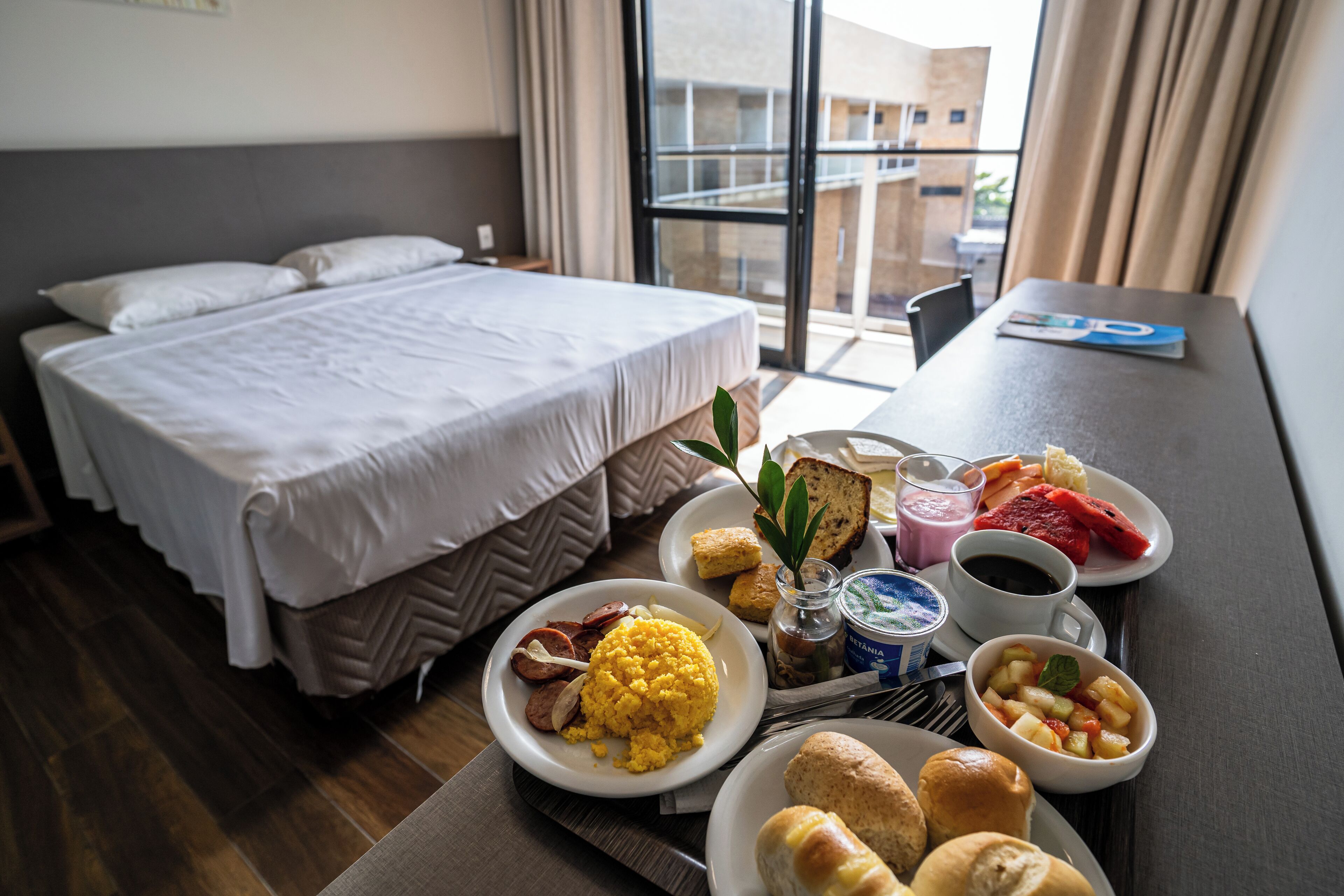 Habitació d'hotel amb un llit, safata de matí amb ous, torrades, fruita i cafè.