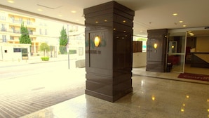 L’entrée d’un hôtel au design moderne, avec une porte en verre et un tapis rouge menant à l’intérieur.