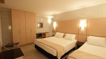 A hotel room with two beds, a desk, and a wardrobe.