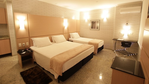 Habitación de hotel con dos camas, un escritorio, una silla, una mesita y un espejo.