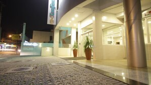 Entrada de hotel con diseño moderno, una recepción y plantas en macetas.