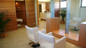 Et moderne receptionområde med hvide læderstole, en receptionsdisk og et stort spejl der reflekterer indretningen.