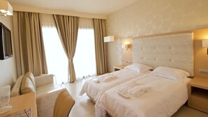 Et hotelværelse med to senge, et skrivebord, en stol og et fjernsyn.