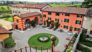 A courtyard with a fountain, outdoor seating, and a building with a red and yellow facade. - Belvivere Suites (Sona)