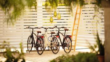 Two bicycles parked against a white slatted fence with hanging decorative elements.